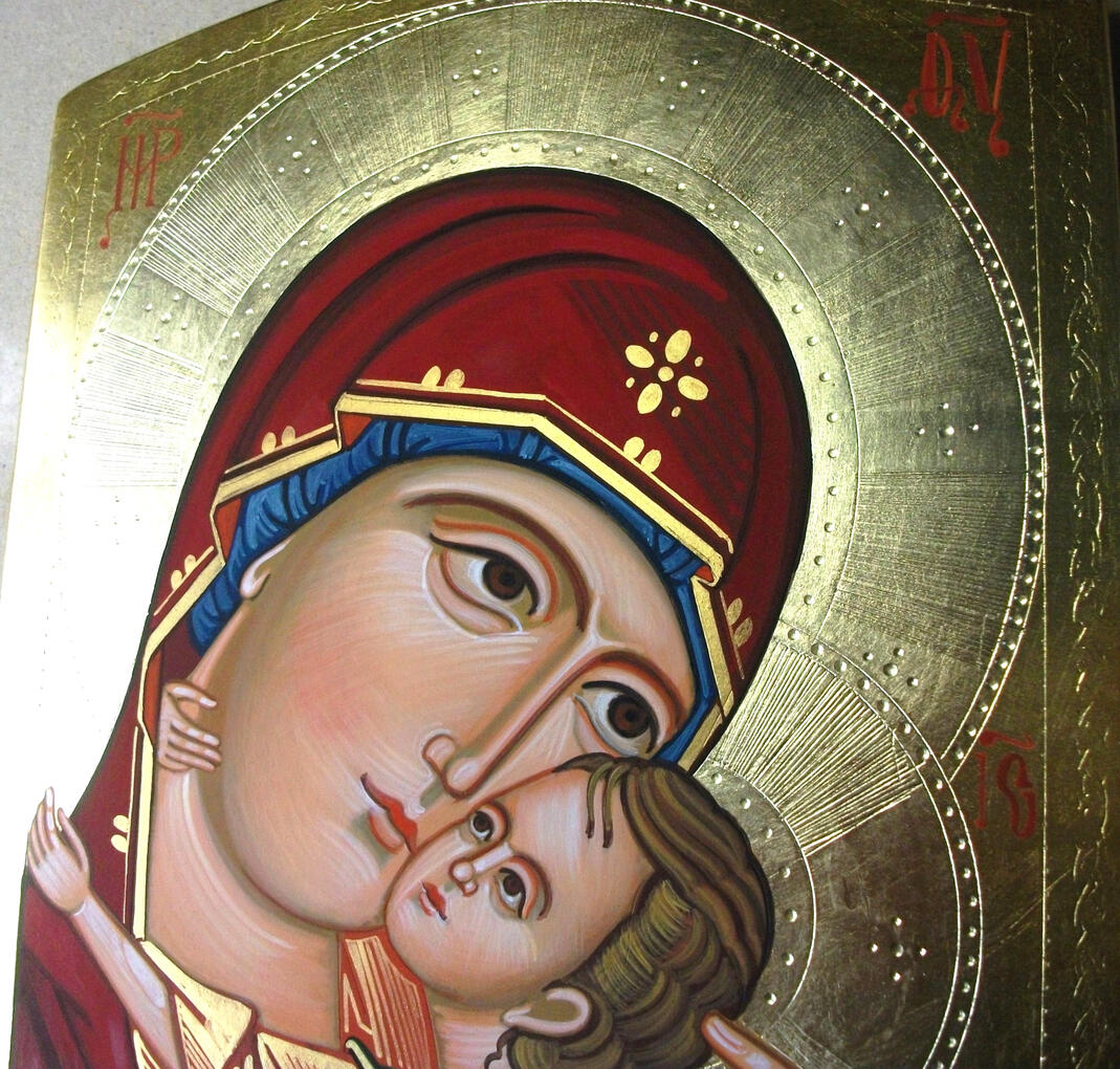 Icona greca della Madonna della Tenerezza (Eleousa) dipinta a mano dal laboratorio iconografico di Nicola Damiano, con la Vergine Maria e il Bambino Gesù accostati guancia a guancia in un tenero abbraccio, manti decorati e sfondo in foglia d'oro.